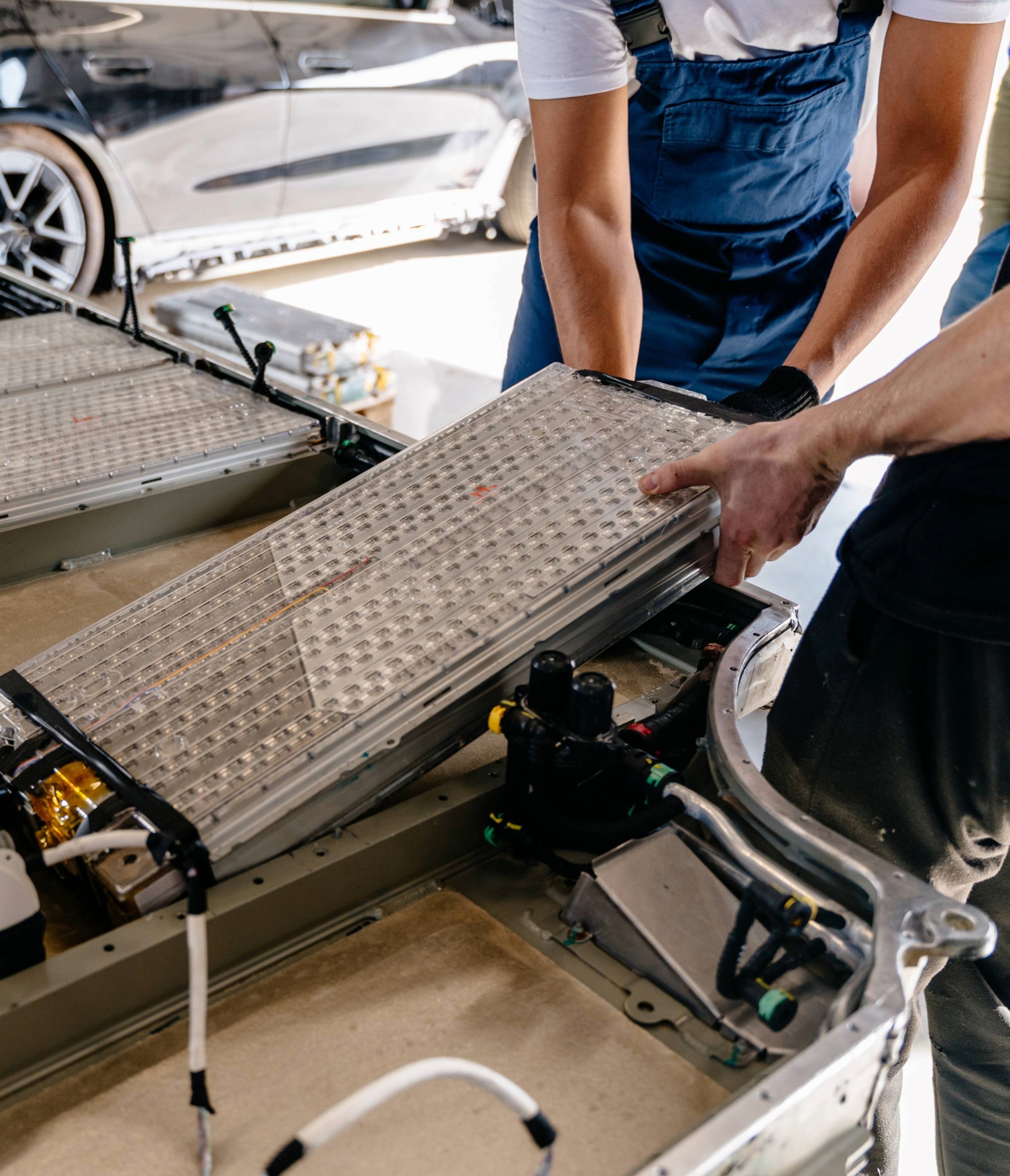 Two technicians lifting up an EV battery component